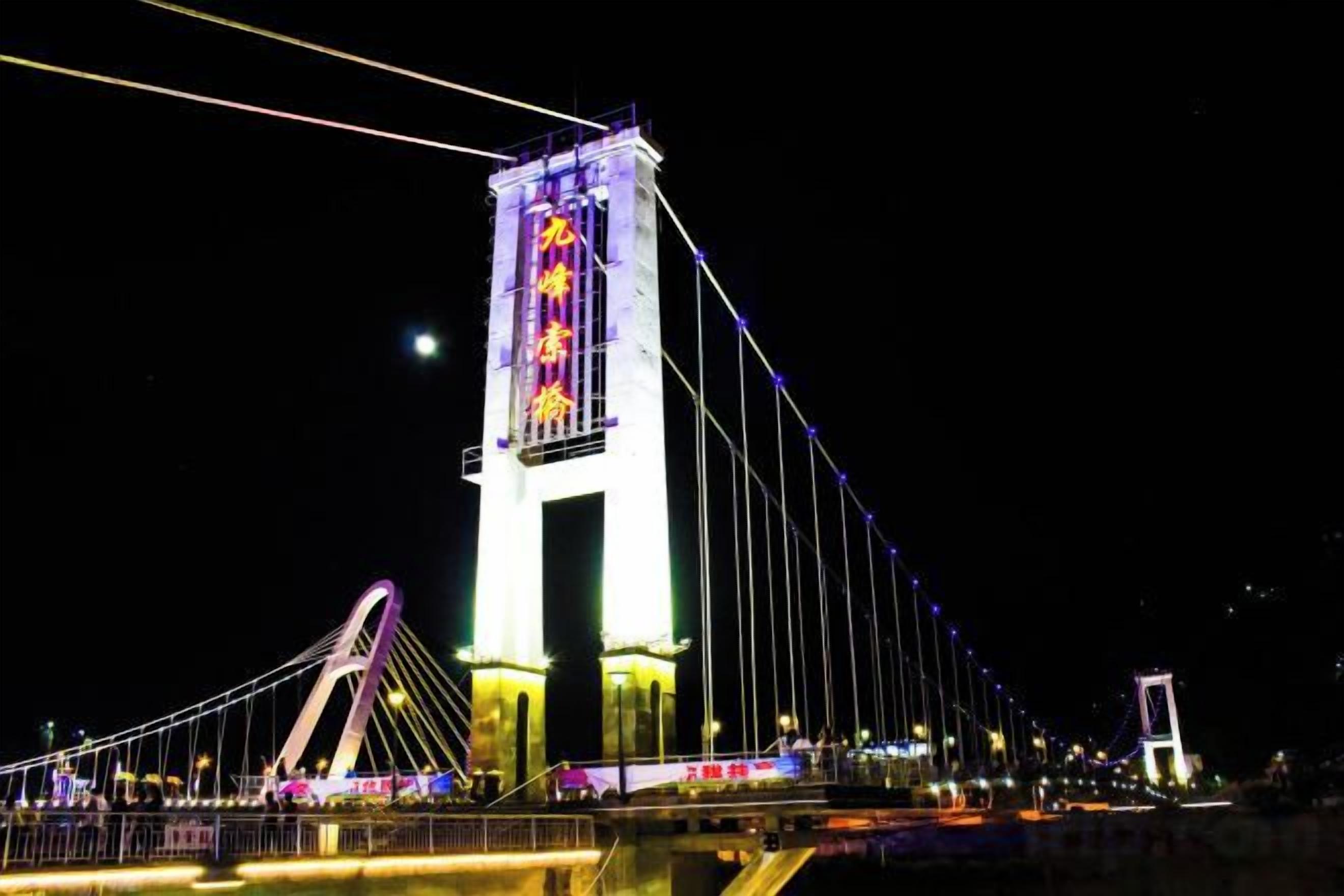Un imponente ponte sospeso con una torre centrale ben visibile, dotato di segnaletica illuminata.
