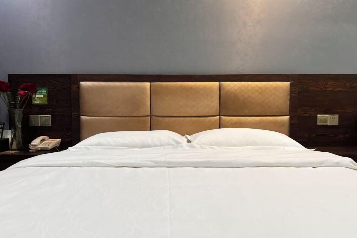 A neatly made bed with a headboard featuring a padded design.