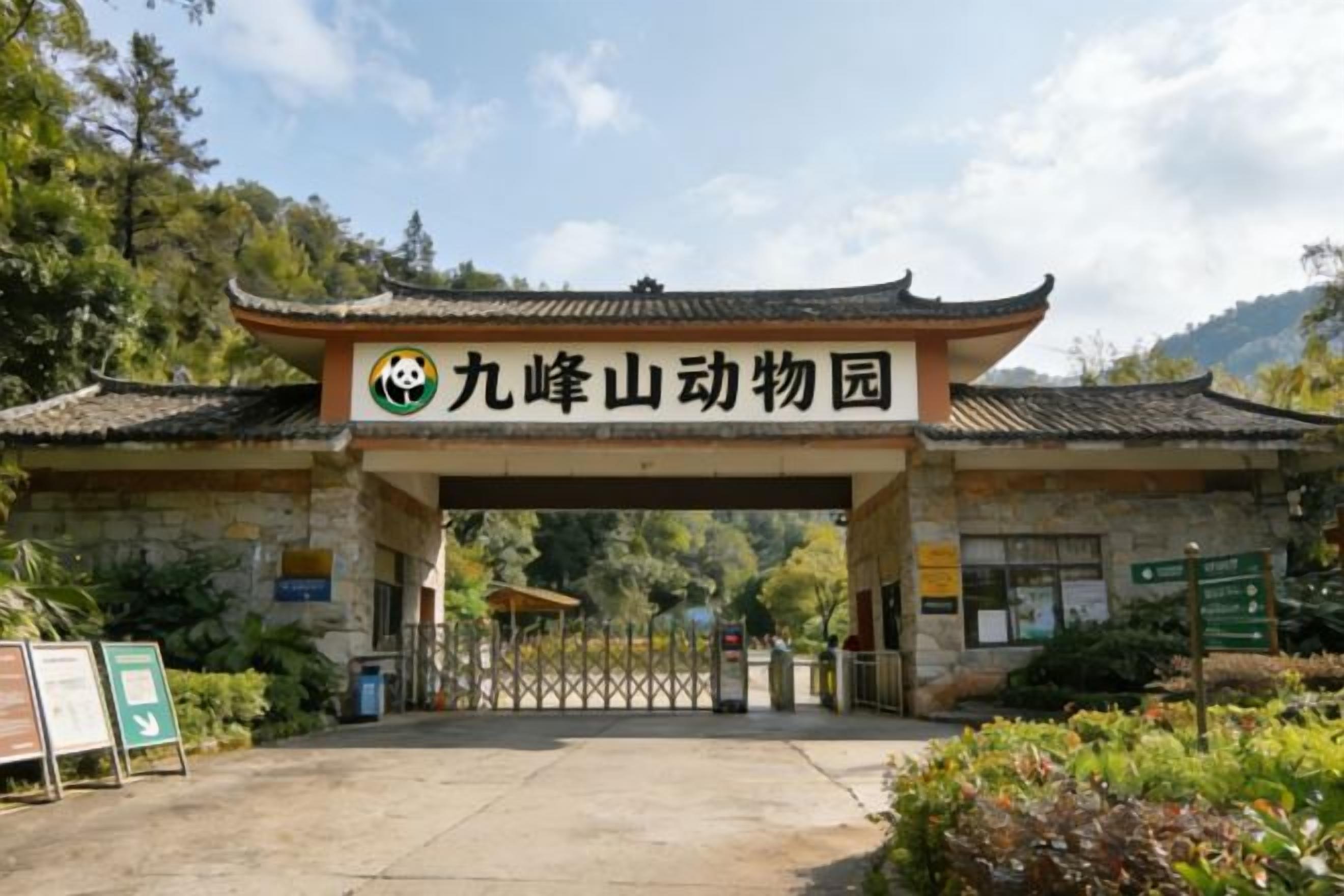 Una puerta tradicional china con un cartel que indica 'Jiu Feng Mountain Animal Park' frente a un edificio de piedra.