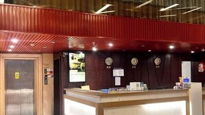 Ein Hotel-Empfangsbereich mit einem Holzbüro, einer Uhr und einem Brandschutznachweis.