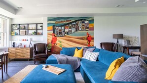 A living room with a blue sectional sofa, a wooden coffee table, and a colorful mural on the wall. - Lake retreat with unique dome near Indiana Dunes (Valparaiso)
