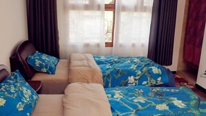 Ein Zimmer mit einem Bett, einem Sessel und einem Vorhangfenster.