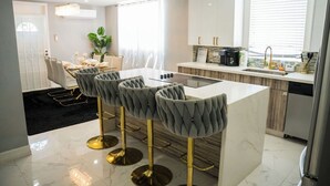 A modern kitchen with white cabinets, a marble countertop, and a black rug.