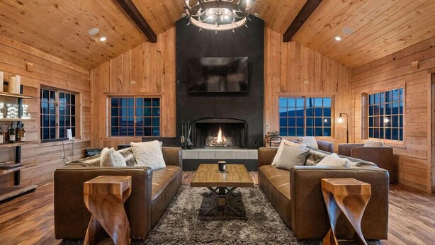 A cozy log cabin interior with a fireplace, leather sofas, and wooden accents. - EML 1 Pack Saddle Jack (Paonia)