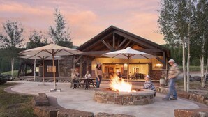 A rustic lodge with a stone fire pit, outdoor seating, and large umbrellas. - EML 1 Pack Saddle Jack (Paonia)