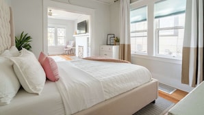 Un dormitorio con una cama grande, un escritorio, una silla, una ventana con cortinas y vistas al exterior.
