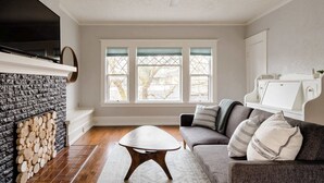 Un salon avec une cheminée, un canapé, une table basse et un téléviseur fixé au mur.