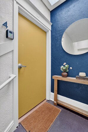Una puerta con marco amarillo, una puerta blanca y un pequeño dispositivo electrónico montado en la pared.