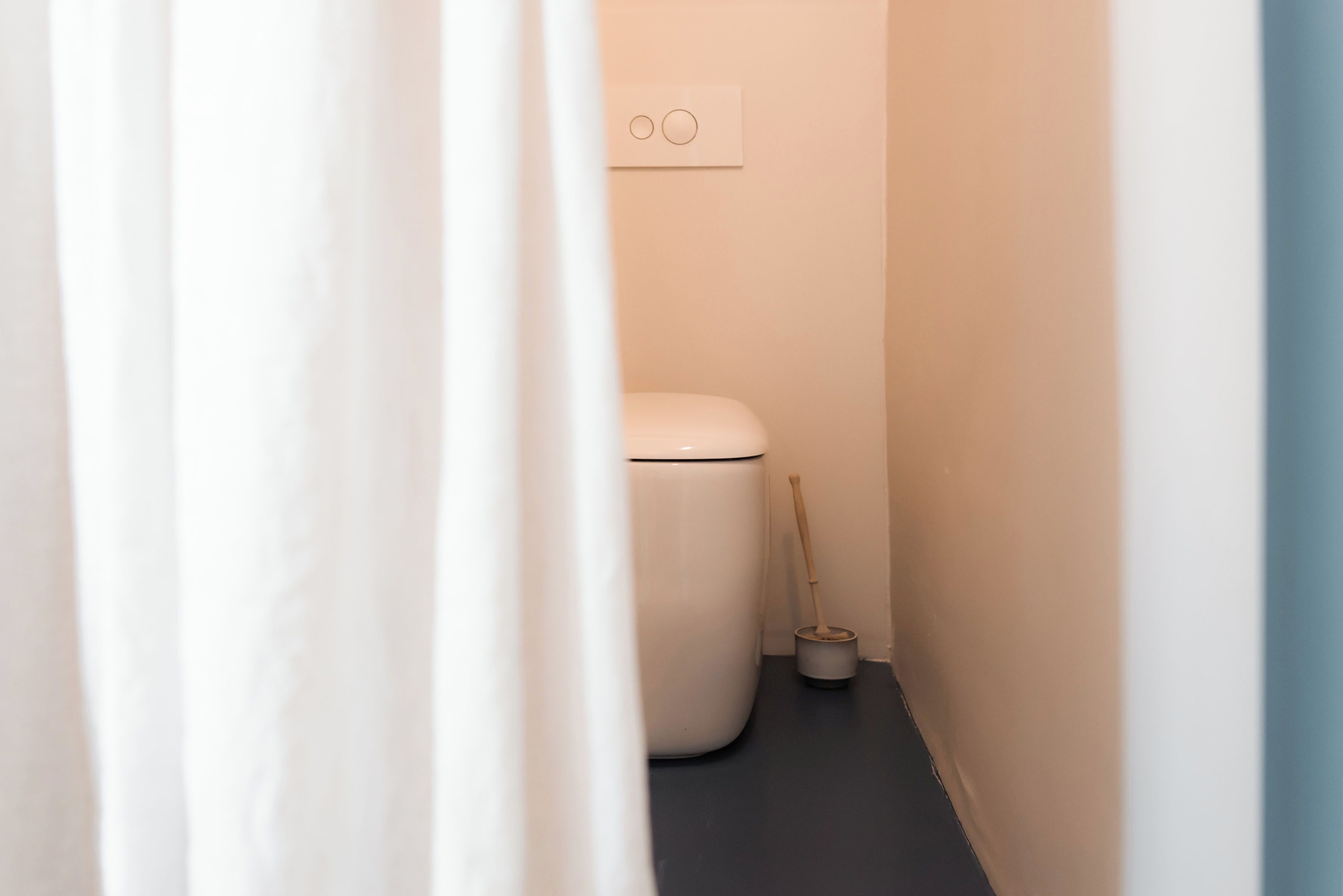 Une petite salle de bain avec des toilettes, une ventouse et un interrupteur sur le mur.