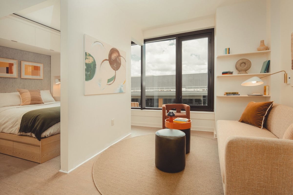 A modern bedroom with a bed, a sofa, a coffee table, and a large window.