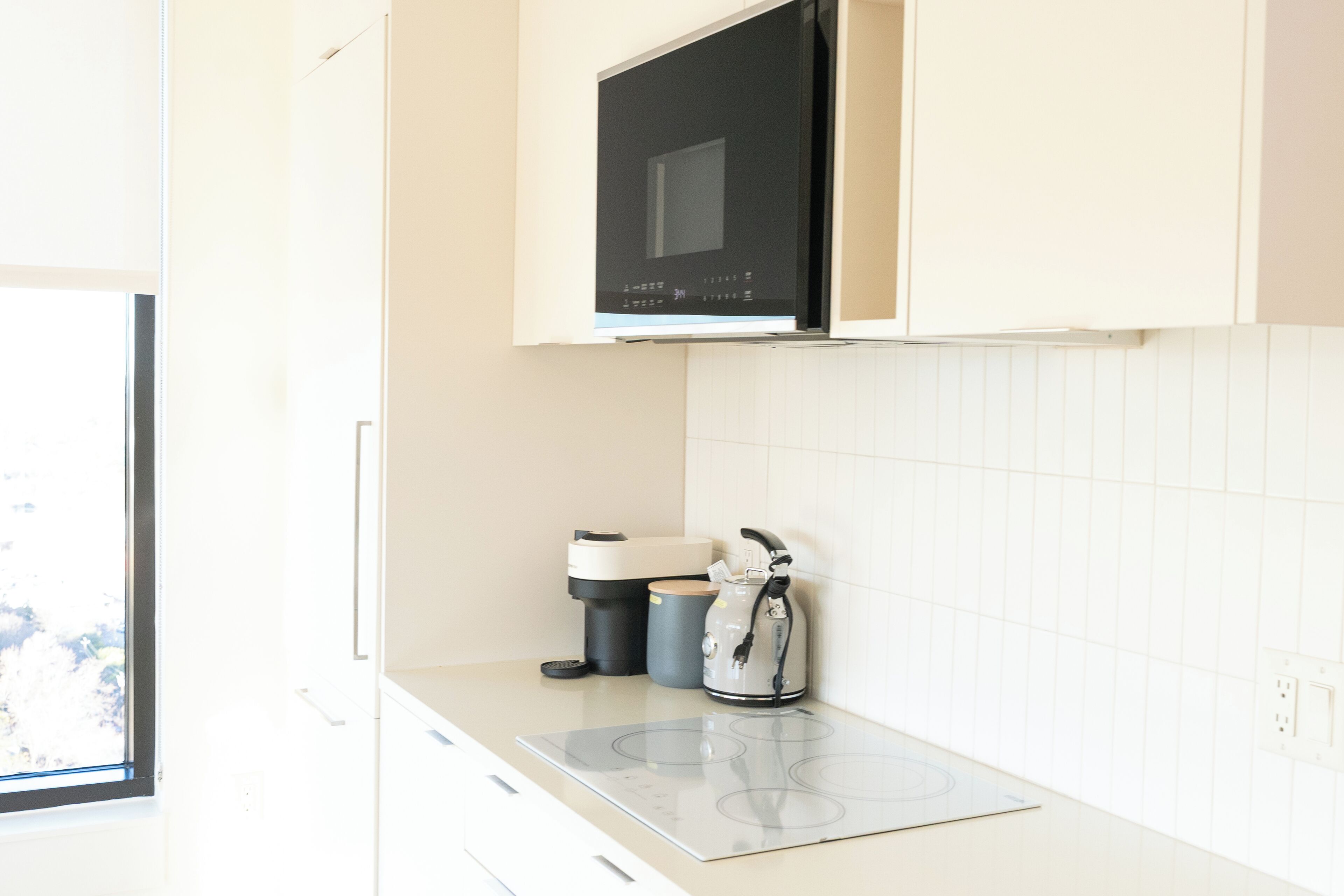 Una cucina con forno a microonde, bollitore e macchina da caffè sul piano di lavoro.