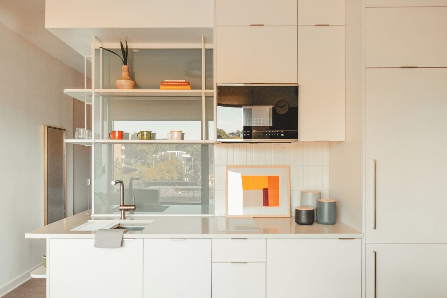 Una cucina moderna con mobili bianchi, piano cottura integrato e una finestra con vista sulla città.