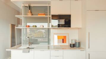 Una cucina moderna con mobili bianchi, piano cottura integrato e una finestra con vista sulla città.