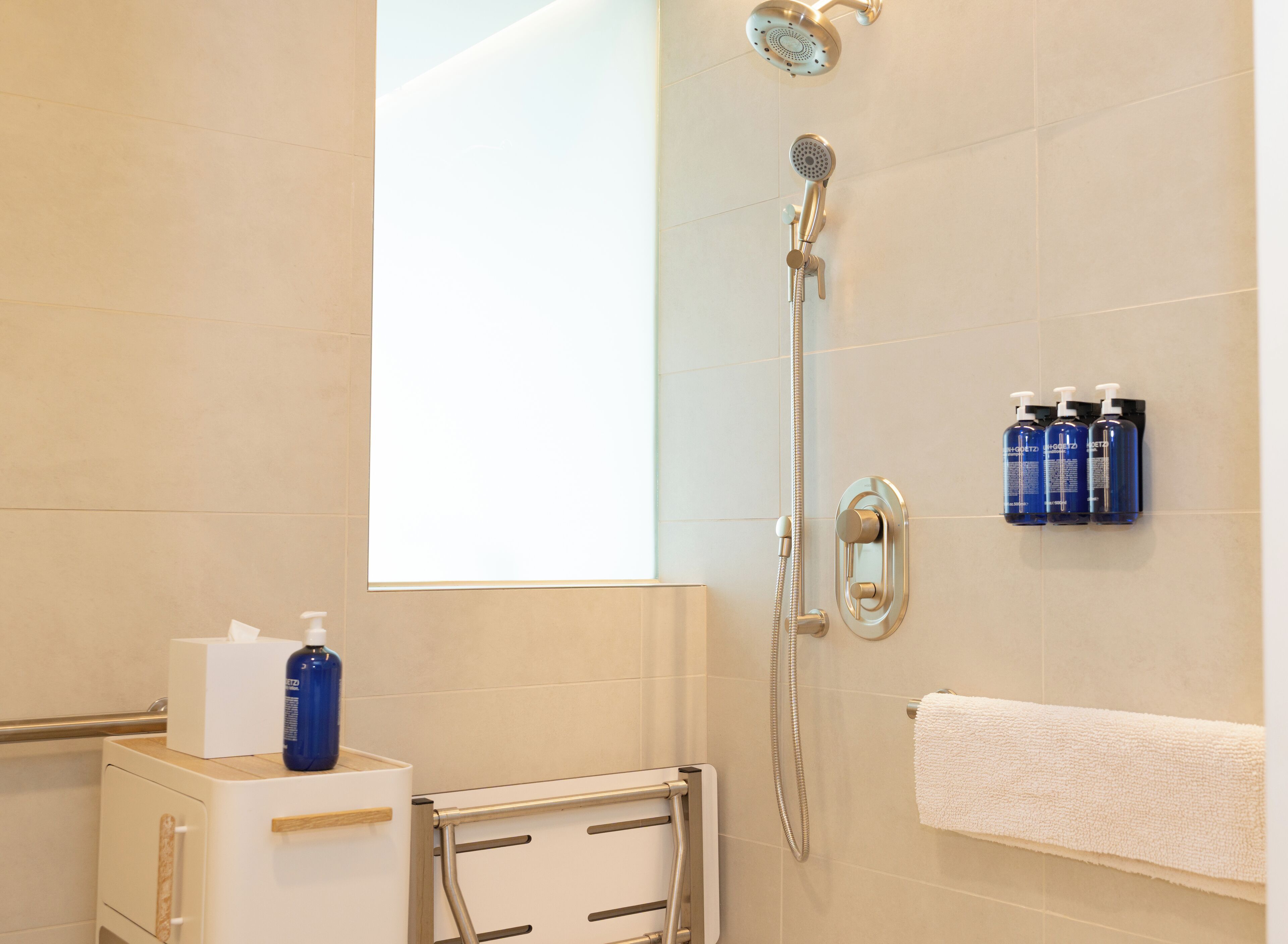 A modern bathroom with a shower, a towel rack, and toiletries.