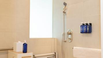 A modern bathroom with a shower, a towel rack, and toiletries.