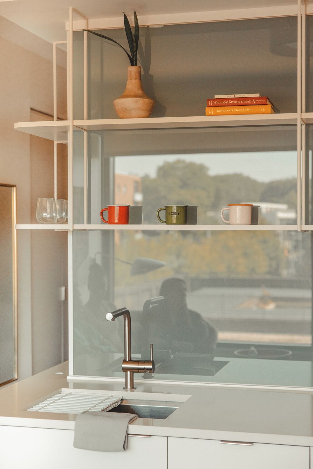 A modern kitchen with a built-in window, a stainless steel faucet, and a white countertop.