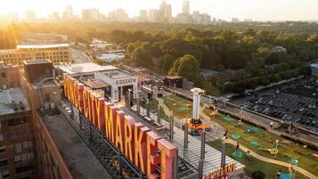 Un mercado al aire libre grande con un letrero llamativo, rodeado de estacionamiento y un horizonte urbano de fondo.
