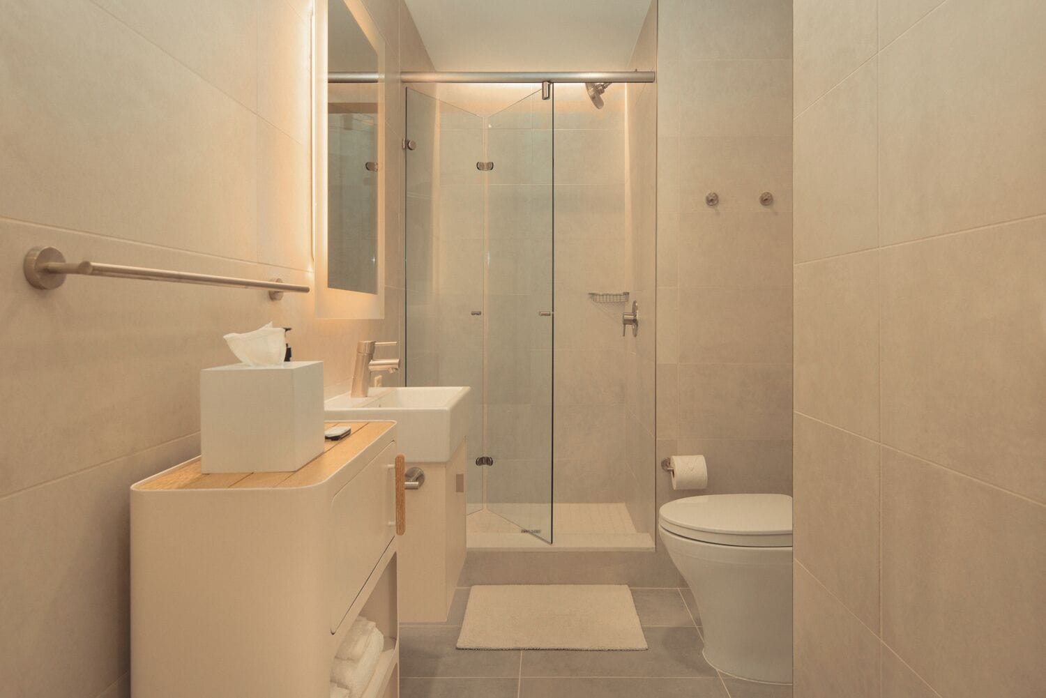 Ein modernes Badezimmer mit Duschkabine aus Glas, Toilette und Waschbecken mit Handtuchhalter.
