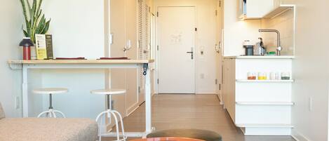 A modern kitchen with white cabinets, a countertop, and a sink. There is a plant on the counter and a coffee machine.