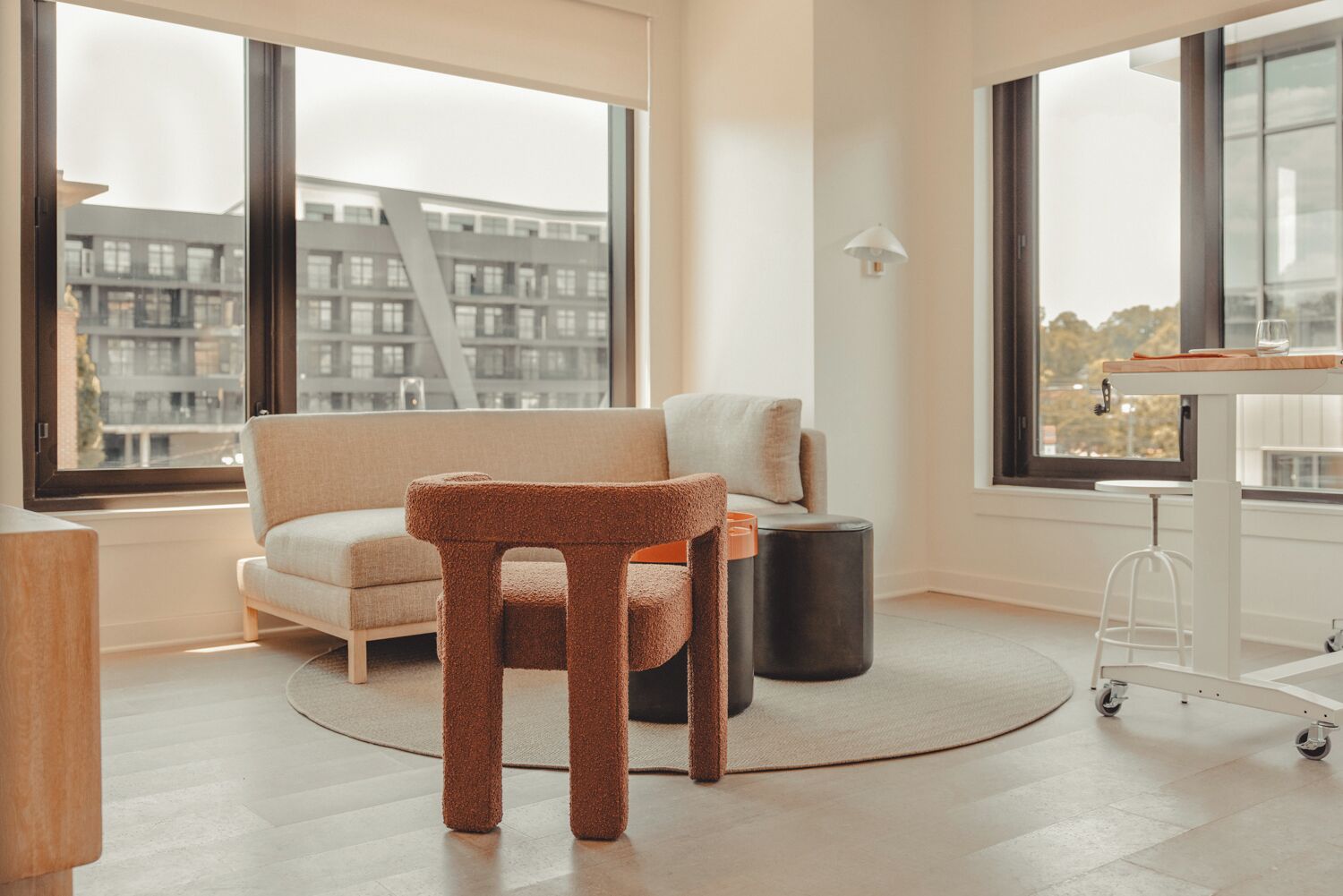 Een moderne woonkamer met een bank, een krabpaal, een kleine tafel en een stadsgezicht door grote ramen.