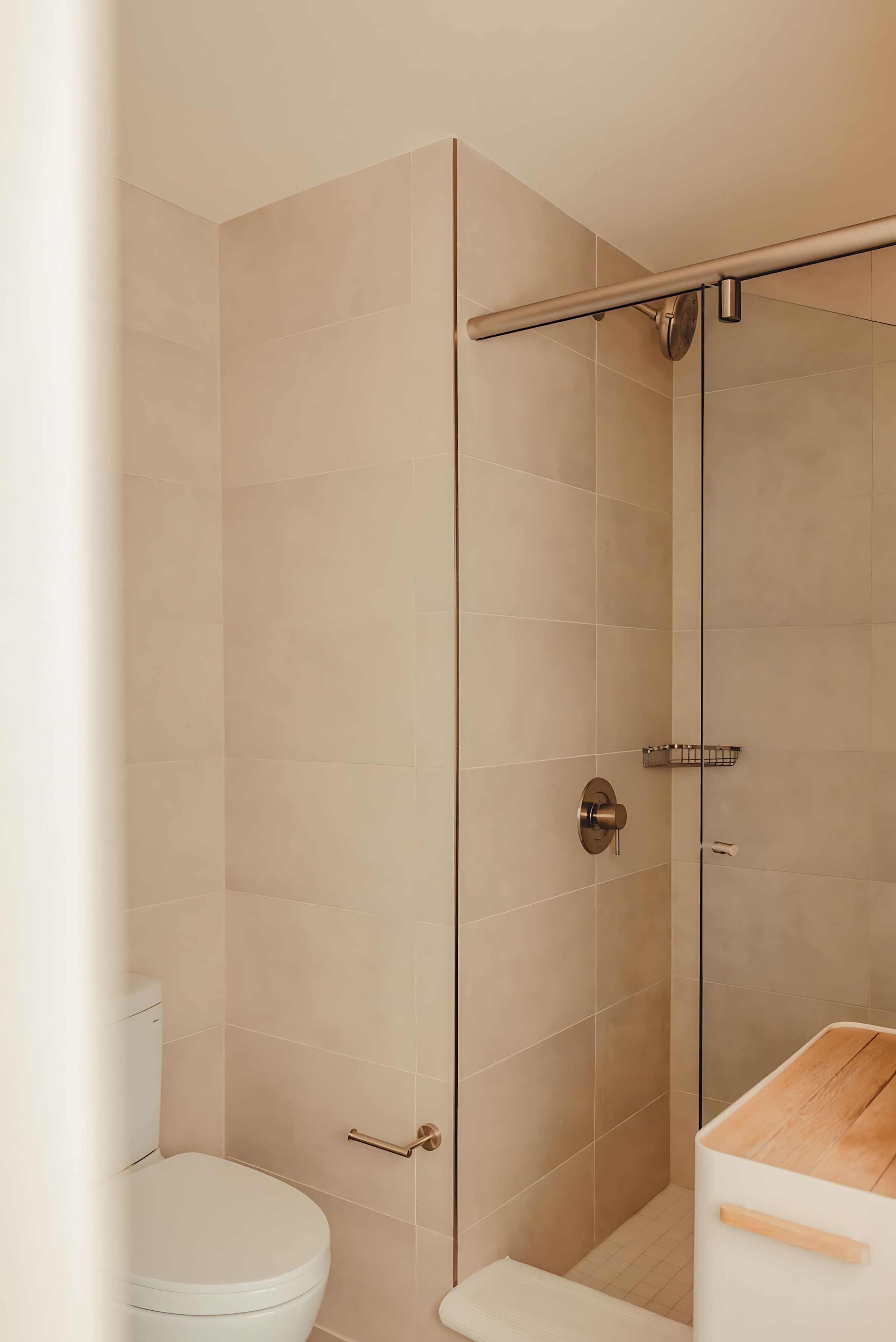 Un baño moderno con cabina de ducha de vidrio, inodoro y tocador de madera.