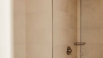 A modern bathroom with a glass shower enclosure, a toilet, and a wooden vanity.
