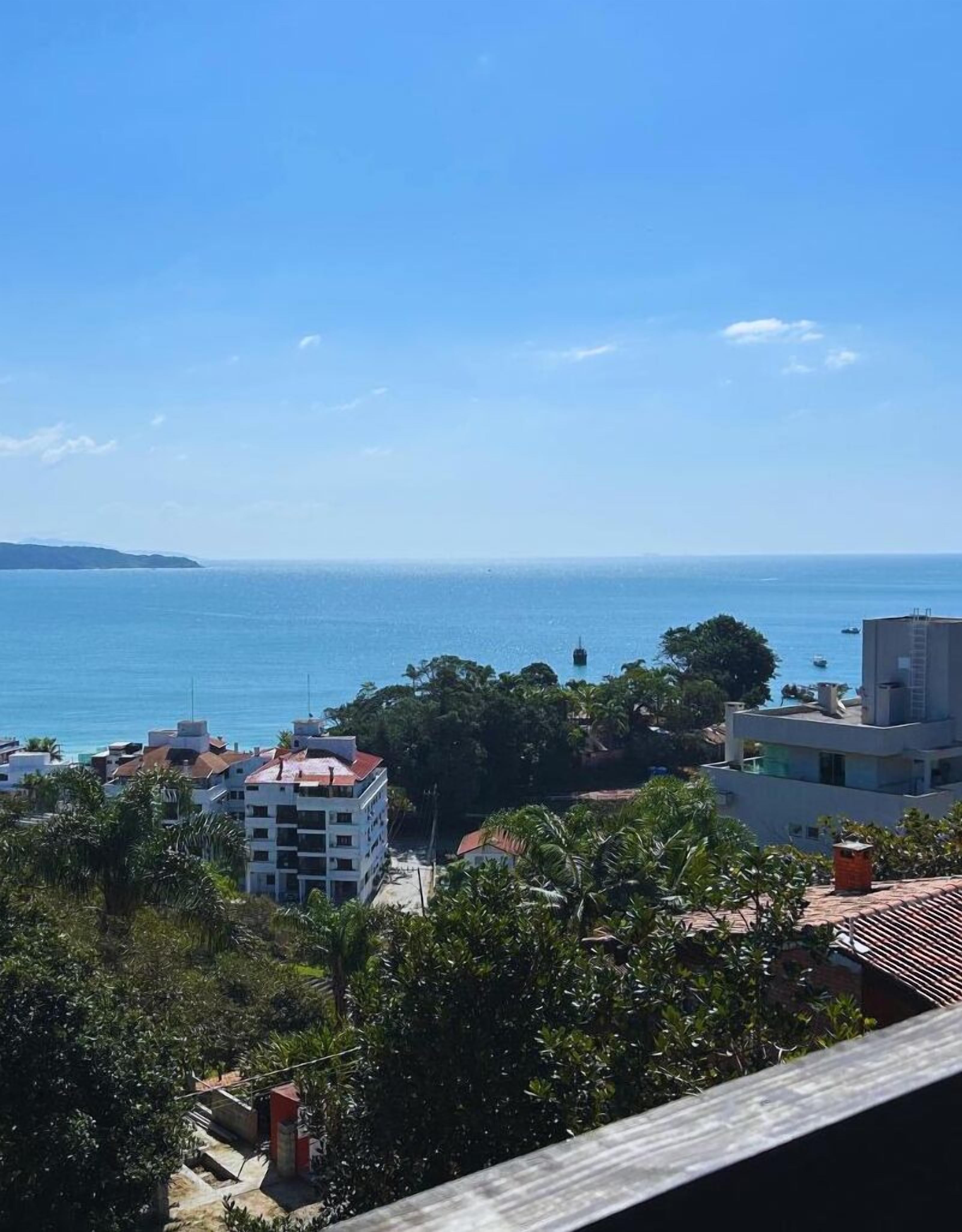Vista costeira com edifícios, árvores e o mar.
