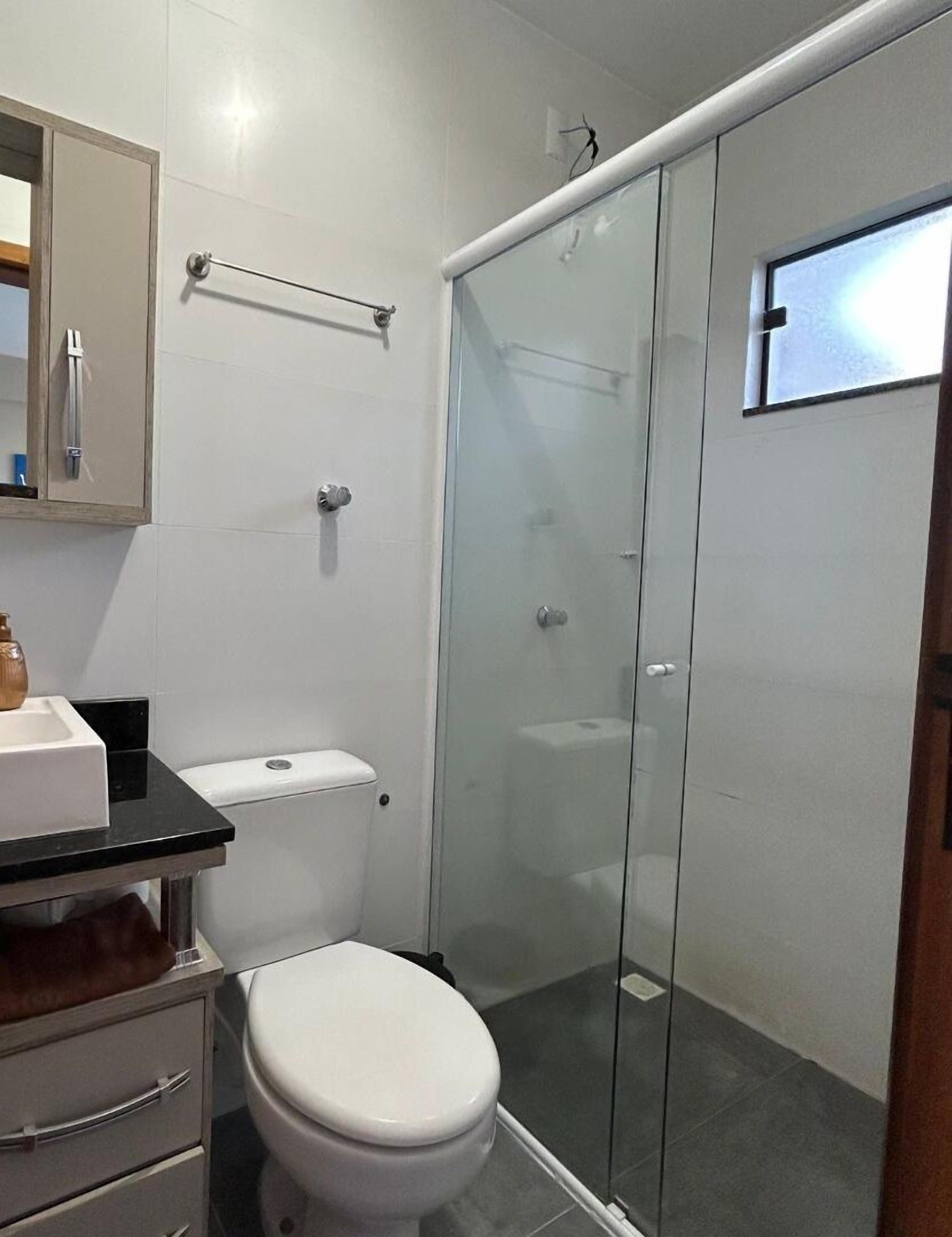 A modern bathroom with a toilet, sink, and glass shower enclosure.