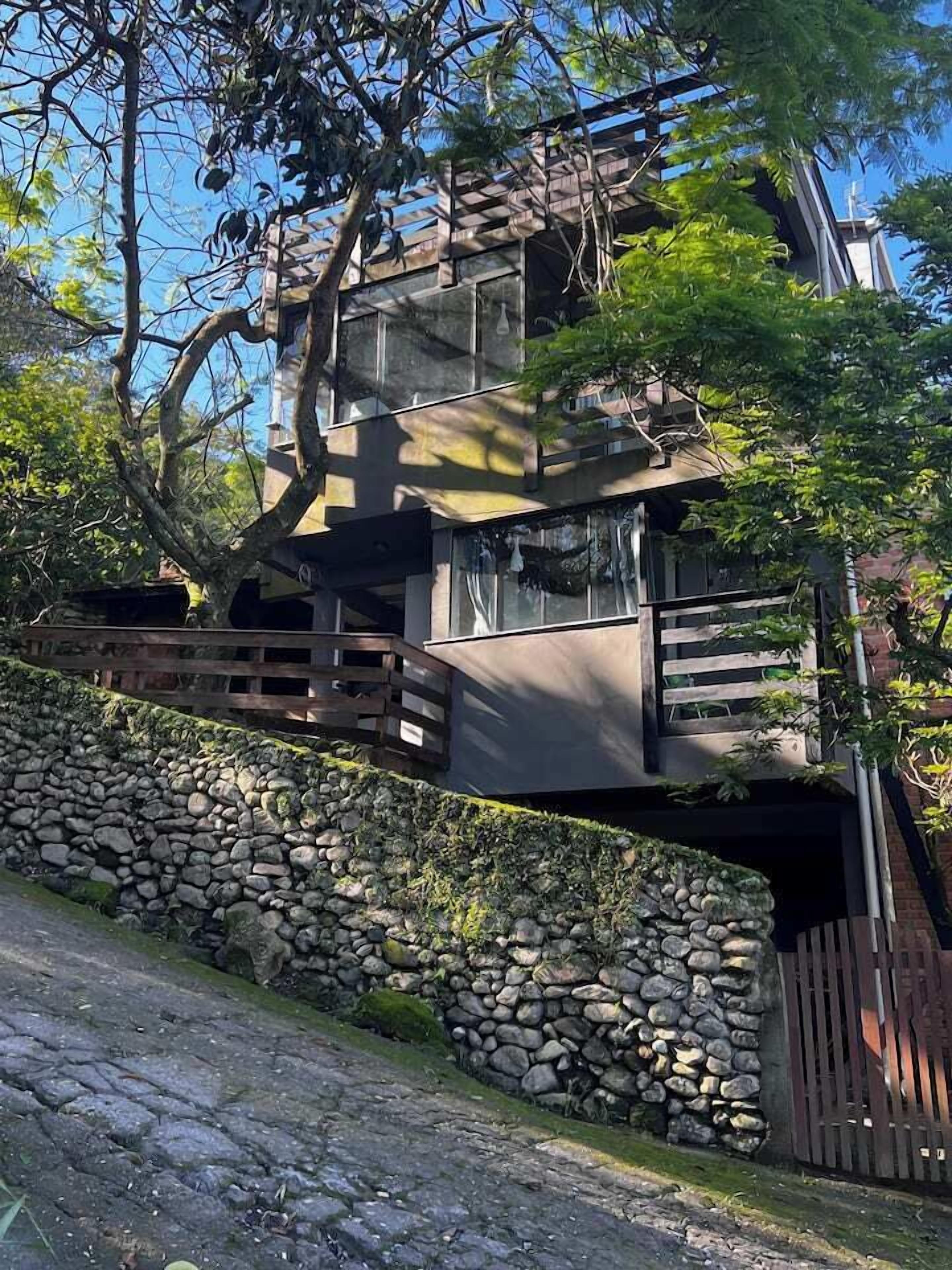 Un immeuble à plusieurs étages, doté d’un mur en pierre et d’une clôture en bois à l’avant.