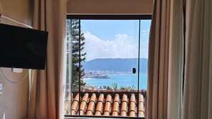 A room with a large window, a ceiling fan, and a flat-screen TV. - Bombinhas Vista Mar (Bombinhas)