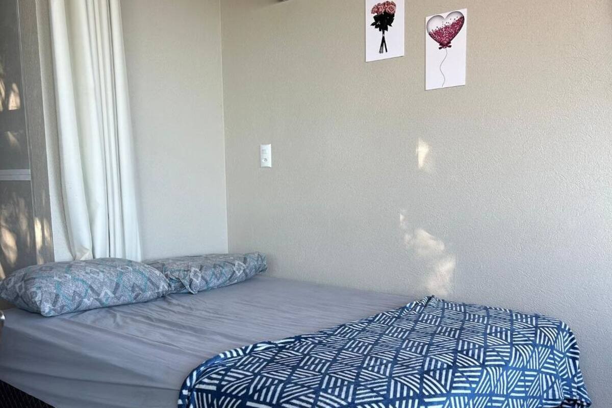 A bedroom with a bed, a patterned blanket, and two wall decorations.