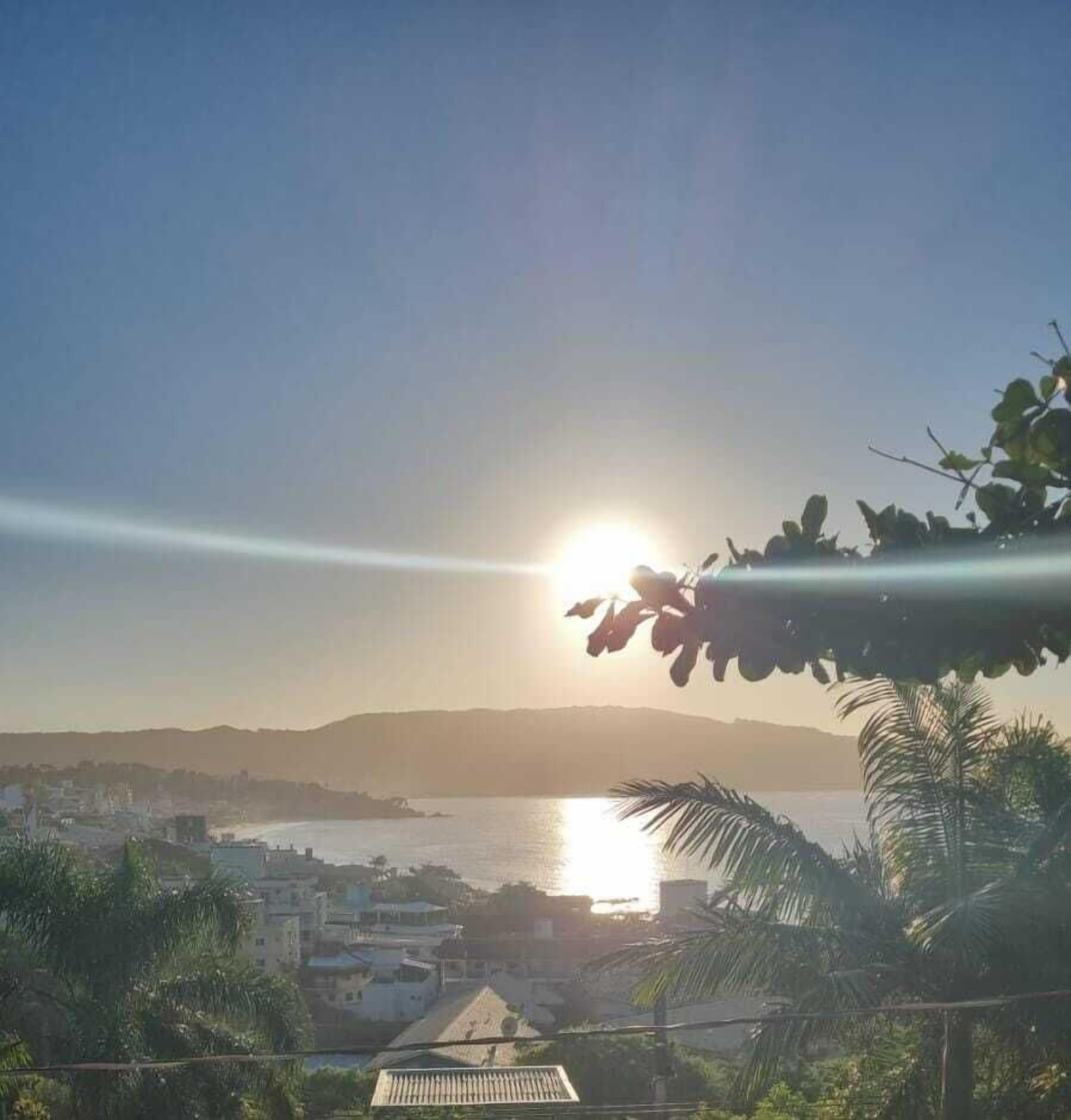 Un paisaje urbano costero con vista despejada al océano y colinas distantes.