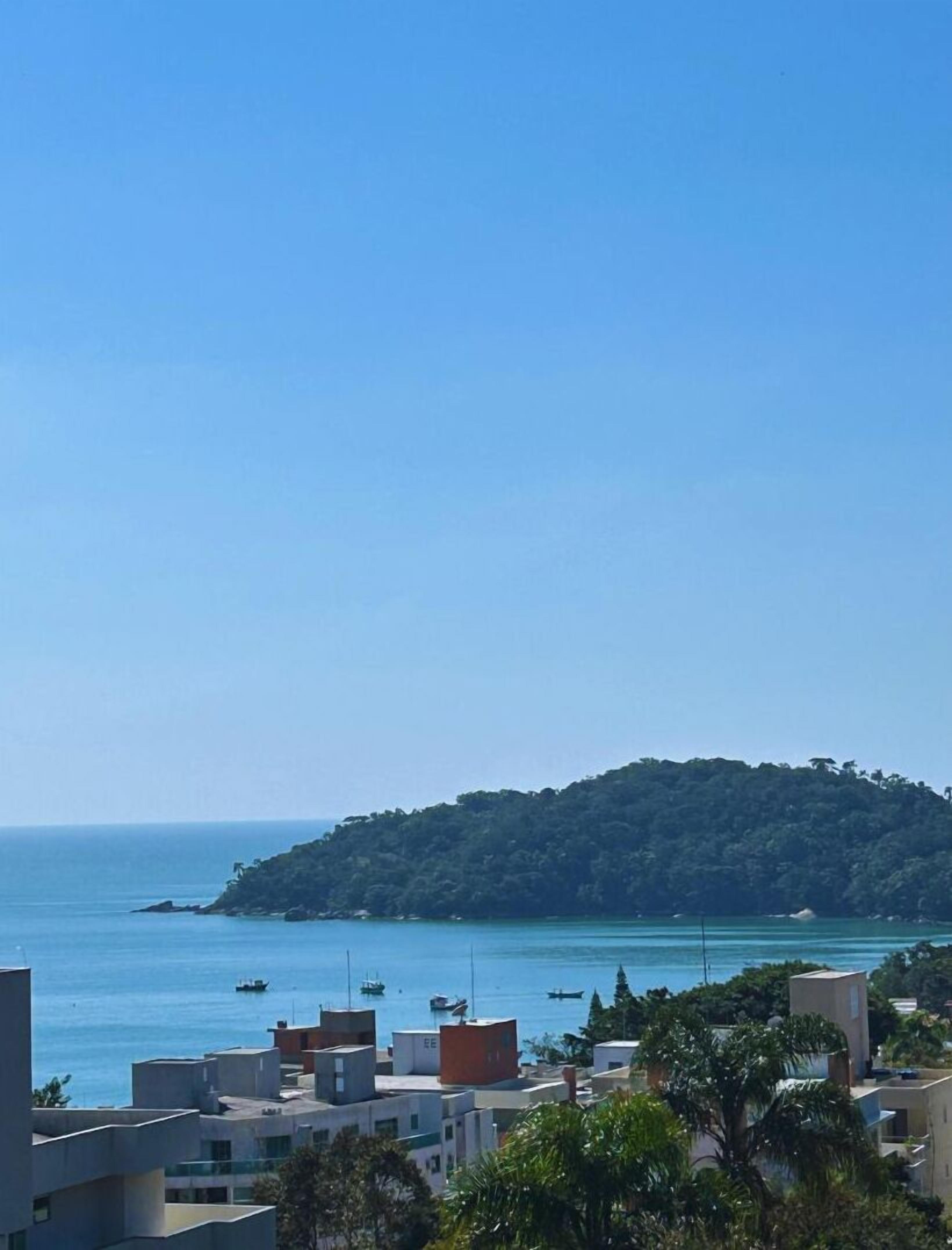 A coastal view with a small island, clear blue sky, and buildings in the foreground.