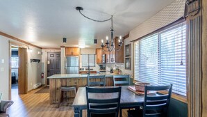 A spacious kitchen with wooden cabinets, a central island, and a dining area with chairs.