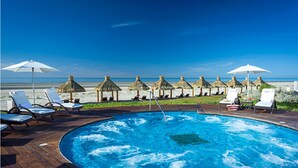A pool area with lounge chairs and umbrellas, overlooking a beach.