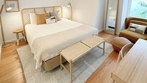 A bedroom with a bed, bedside tables, a bench, a mirror, and a window. - Bombarda 15 Evora (Évora)