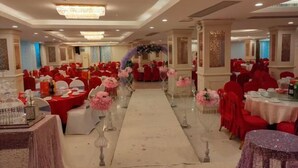 Un salón de banquetes con mesas redondas, sillas rojas y un pasillo central.