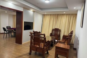 Una sala de estar con muebles de madera, un televisor de pantalla plana y un ventanal con cortinas.