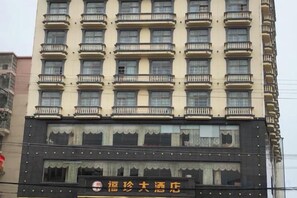 Un edificio de hotel de varios pisos con balcones, un letrero y una fachada con detalles decorativos.