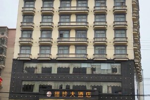 Un edificio de hotel de varios pisos con balcones, un letrero y una fachada con detalles decorativos.