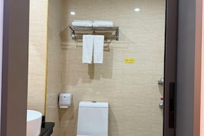 Un baño con inodoro, toallero y dispensador de jabón.