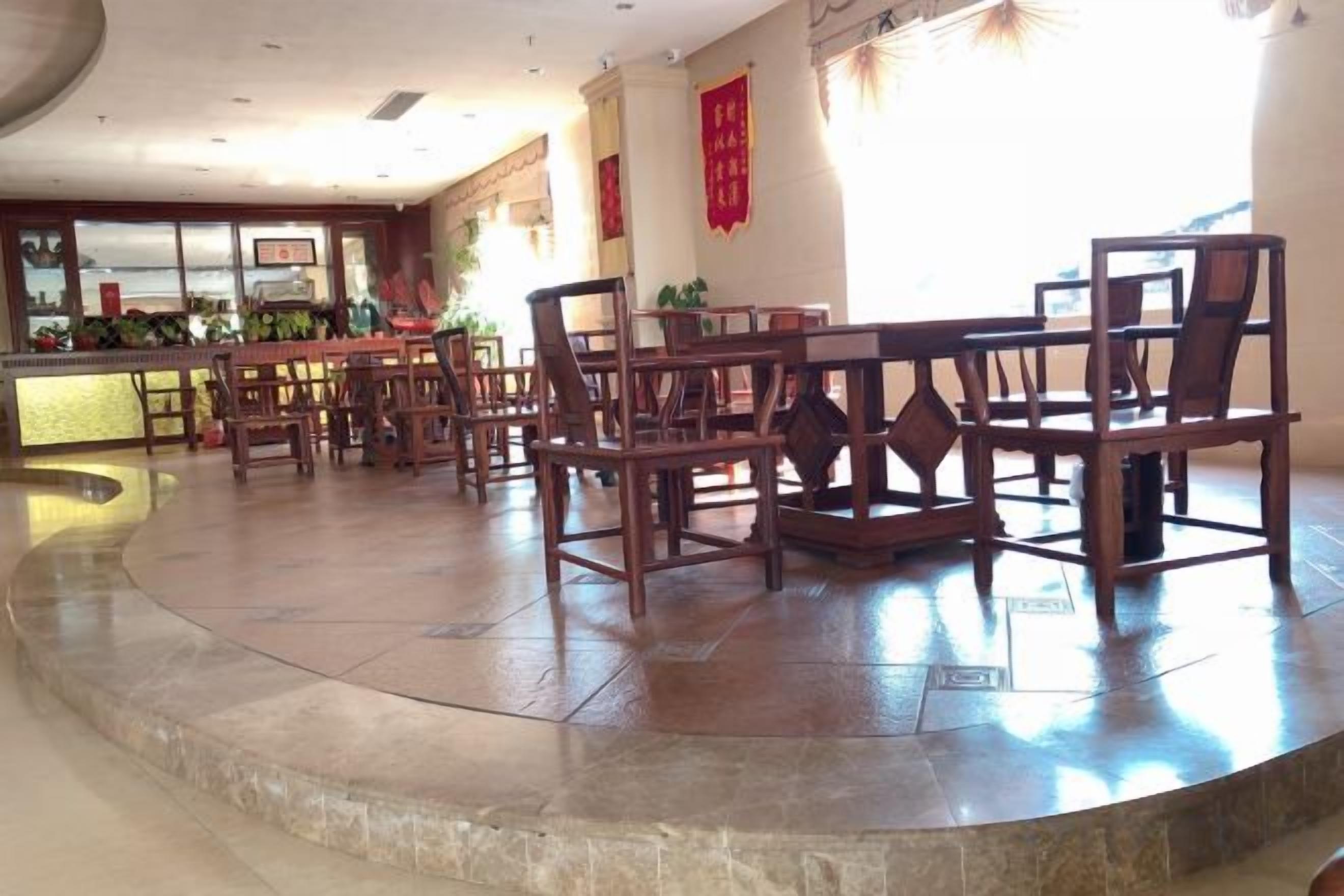 A hotel lobby with a curved seating area, a reception desk, and a large window.