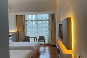 A hotel room with two beds, a desk, a chair, a large window with curtains, and a wall-mounted TV. - Dongxing Fuzhen Hotel (Dongxing)