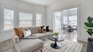 Een moderne woonkamer met een modulaire bank, een ronde salontafel en een eethoek met een tafel en stoelen.