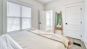 Een slaapkamer met een groot bed, witte muren en een houten ladder die tegen een deur leunt.
