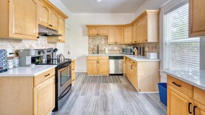 Een moderne keuken met houten kastjes, roestvrijstalen apparatuur en een kamerbreed tapijt met patroon.