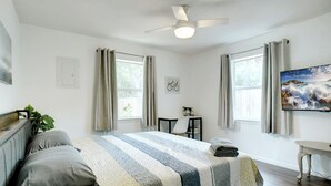 Een slaapkamer met een bed, een bureau, een stoel en een schilderij aan de muur.