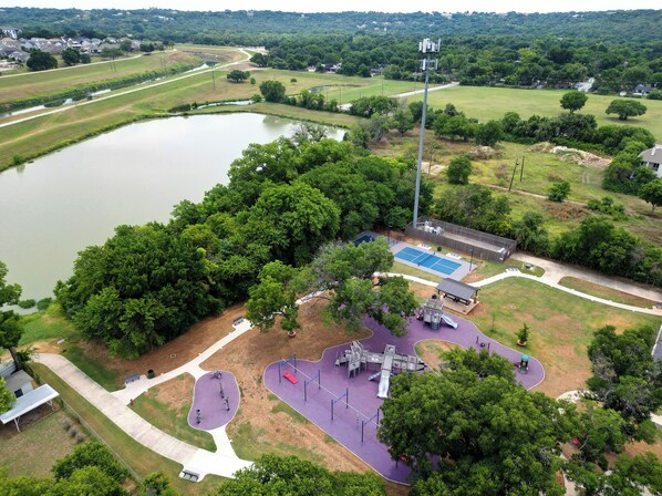 A park with a playground, a basketball court, and a pond. - Charming King Bed House Centrally Located with Fast WiFi (Fort Worth)