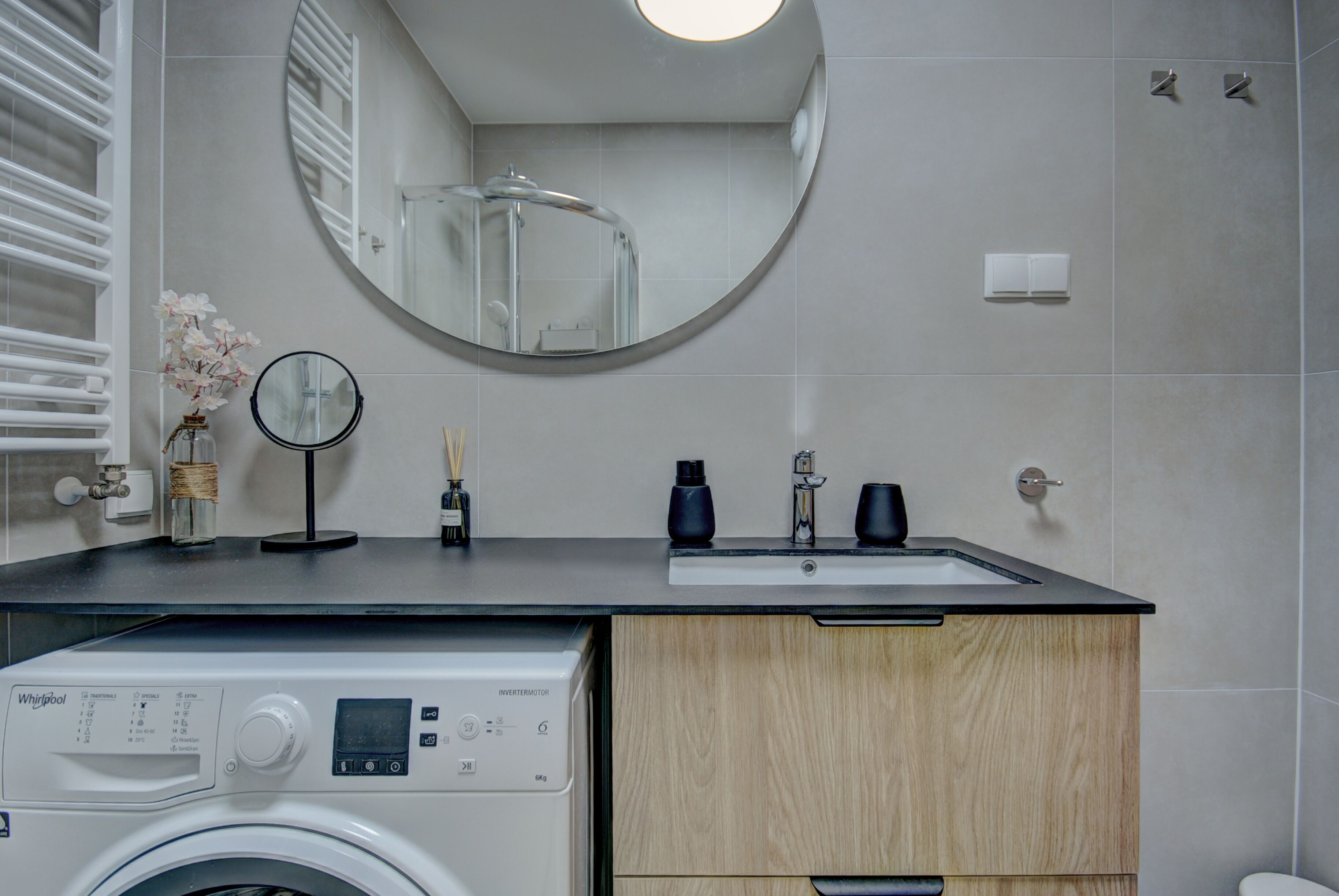 Un baño moderno con lavadora, un lavamanos y un espejo.