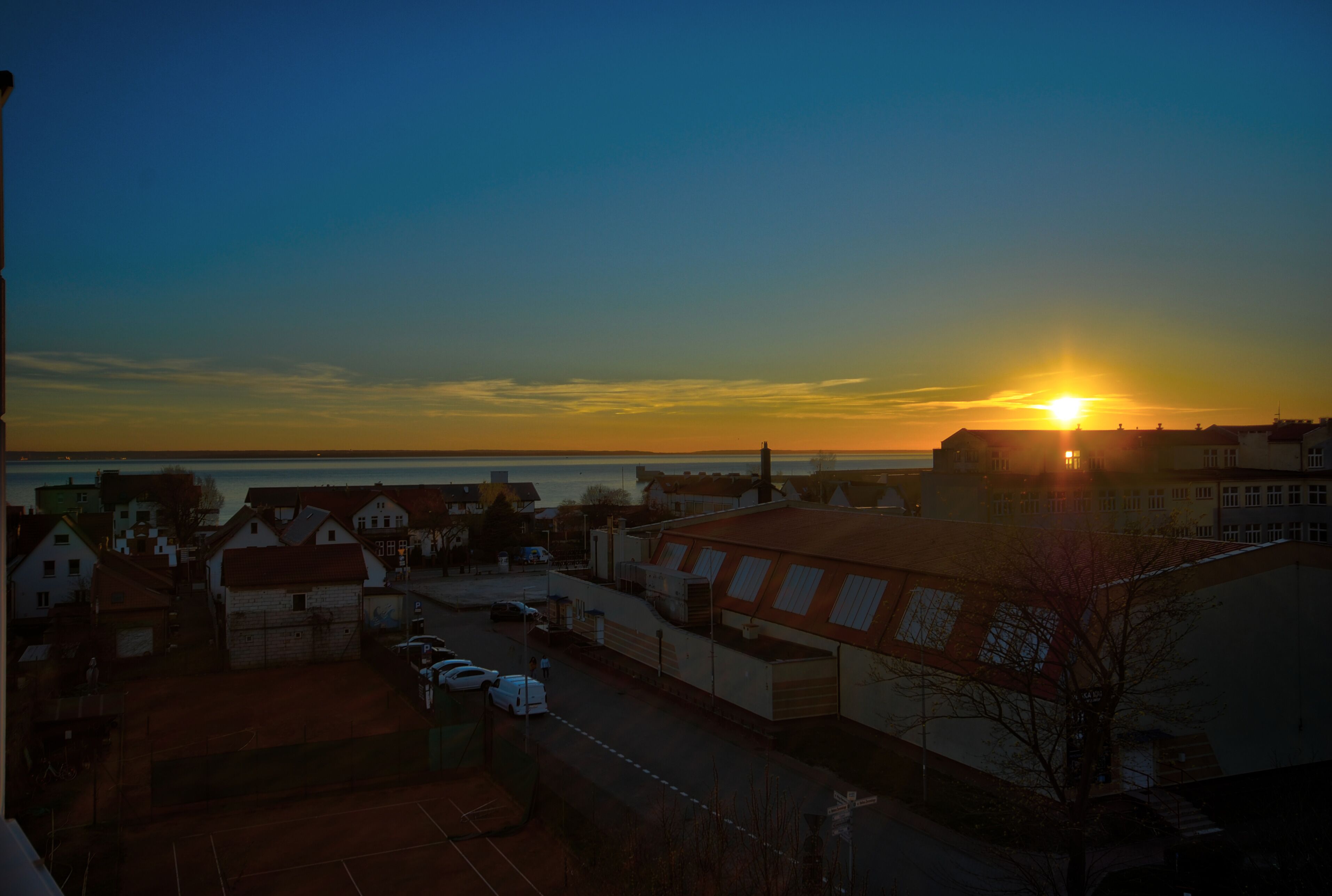 A sunset over a residential area with houses and a body of water.